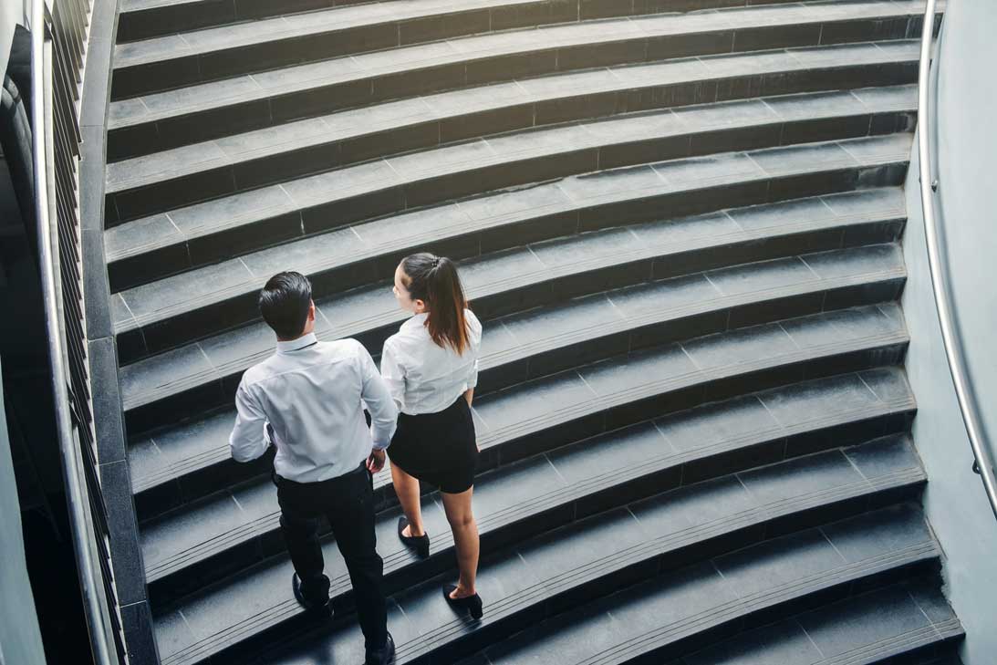 Zwei Arbeitskollegen gehen eine Treppe hoch für mehr Bewegung im Alltag