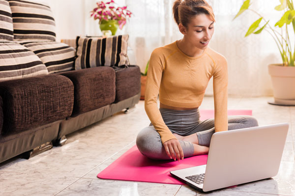 Eine Frau macht Yoga vor dem Laptop für mehr Bewegung im Home office